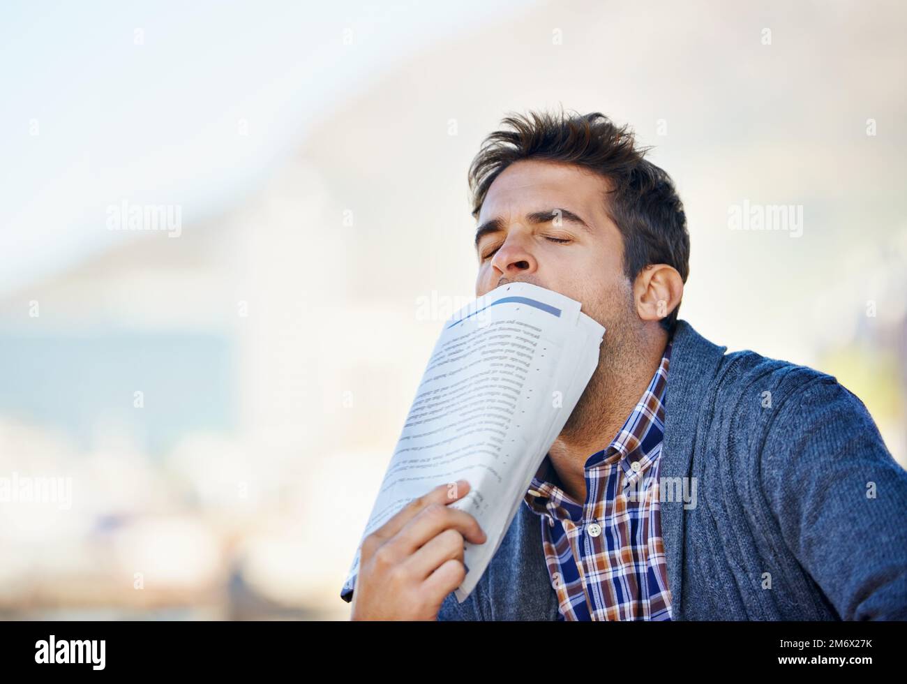 Nothing new today. a man looking tired while holding a newspaper. Stock Photo