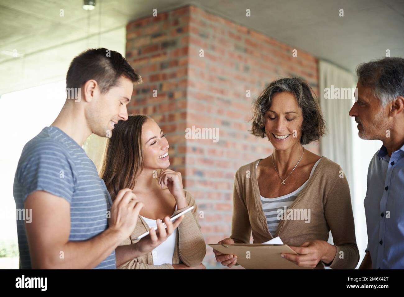 Catching up with mom and dad. A happy family with adult children standing and chatting in their home. Stock Photo