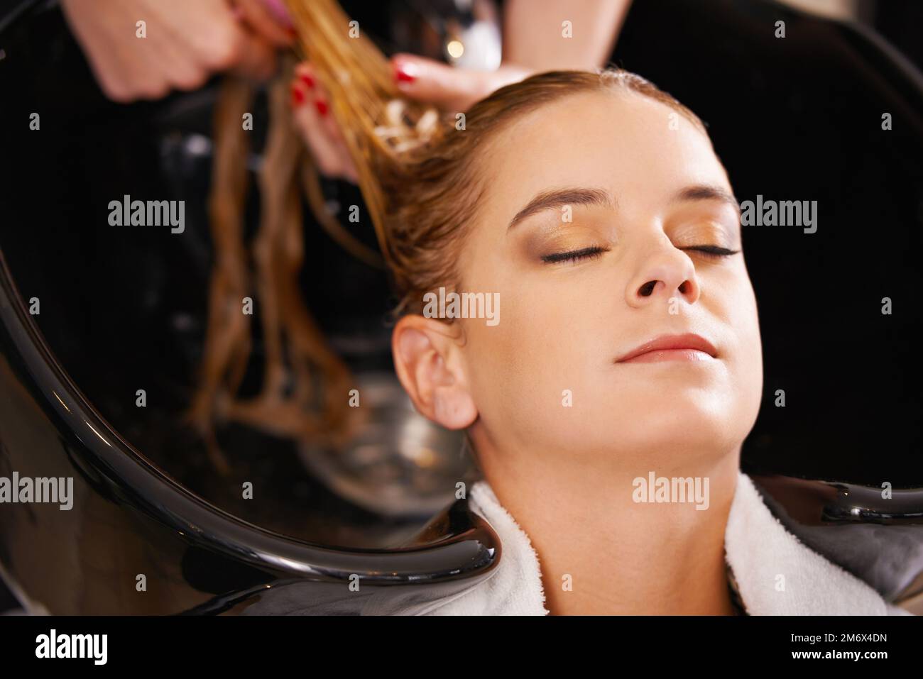 Happiness is a day at the salon. a young woman having her hair washed at a hair salon. Stock Photo