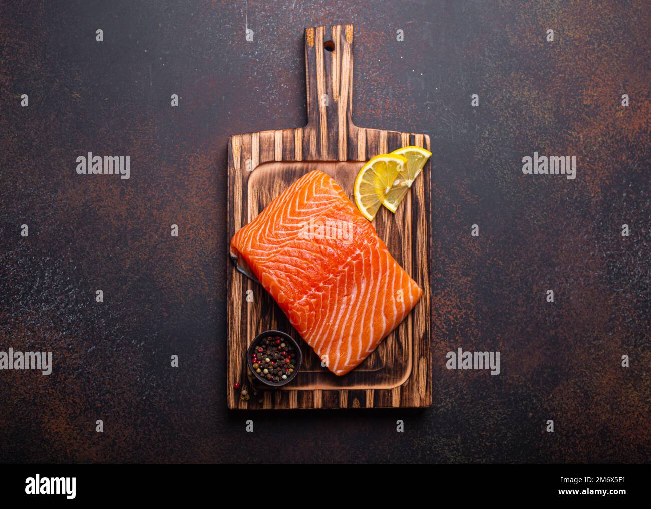 Fresh raw salmon fillet on wooden kitchen cutting board with seasonings ...