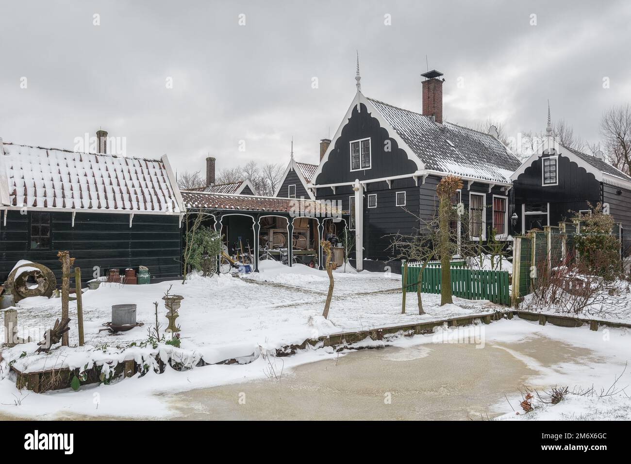 Zaandam, Netherlands, February 10, 2021:Winter landscape with frozen canal and traditional wooden house in Zaanse Schans, Netherlands. Stock Photo