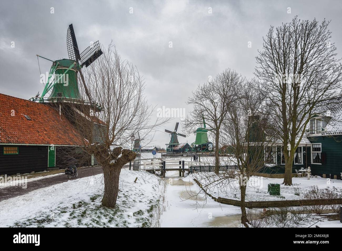 Zaandam, Netherlands, February 10, 2021:Winter landscape with frozen canal and traditional wooden house in Zaanse Schans, Netherlands. Stock Photo
