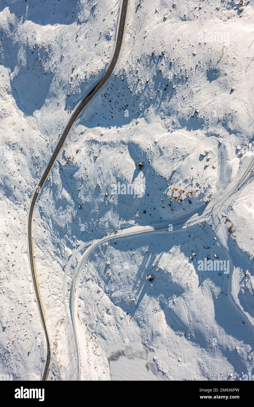 An aerial vertical view of a road in the snowy white field on the ...