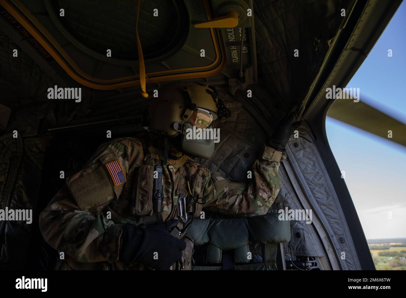 Spc. Heath Dwight, flight crew assigned to the 2nd Battalion, 3rd General Support Aviation Battalion, Hunter Army Airfield, Ga., looks out of the side door of a CH-47 Chinook as it nears its landing zone May 8, 2022. The helicopter evacuated about 15 exercise Guardian Response 22 role players to a safe zone after a simulated nuclear bomb was detonated near their homes. Guardian Response 22 is an annual homeland emergency exercise designed to sharpen the skills, boost capabilities and improve mission readiness of U.S. Army units assigned to the Department of Defense’s Chemical, Biological, Radi Stock Photo