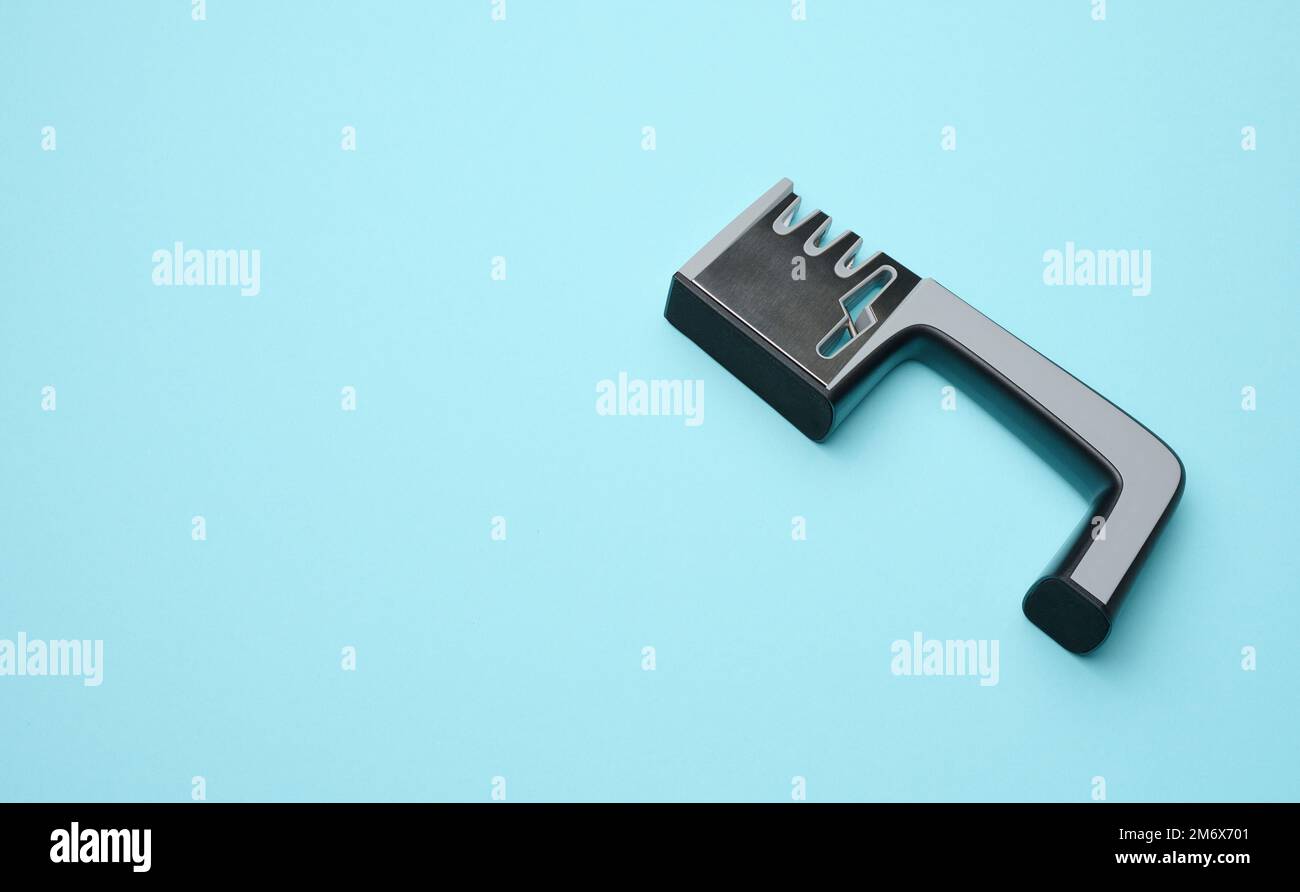 Manual sharpener for kitchen knives on a blue background Stock Photo