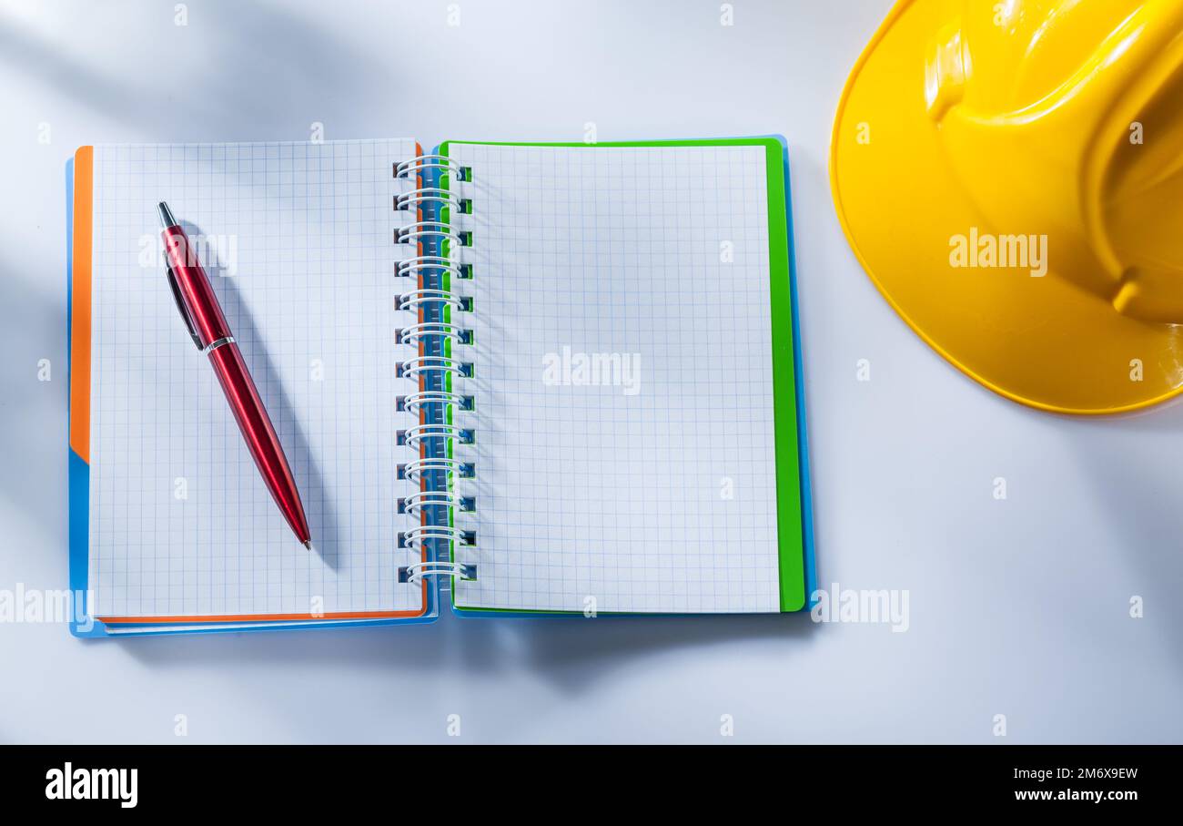 Building helmet checked notepad pen on white background. Stock Photo