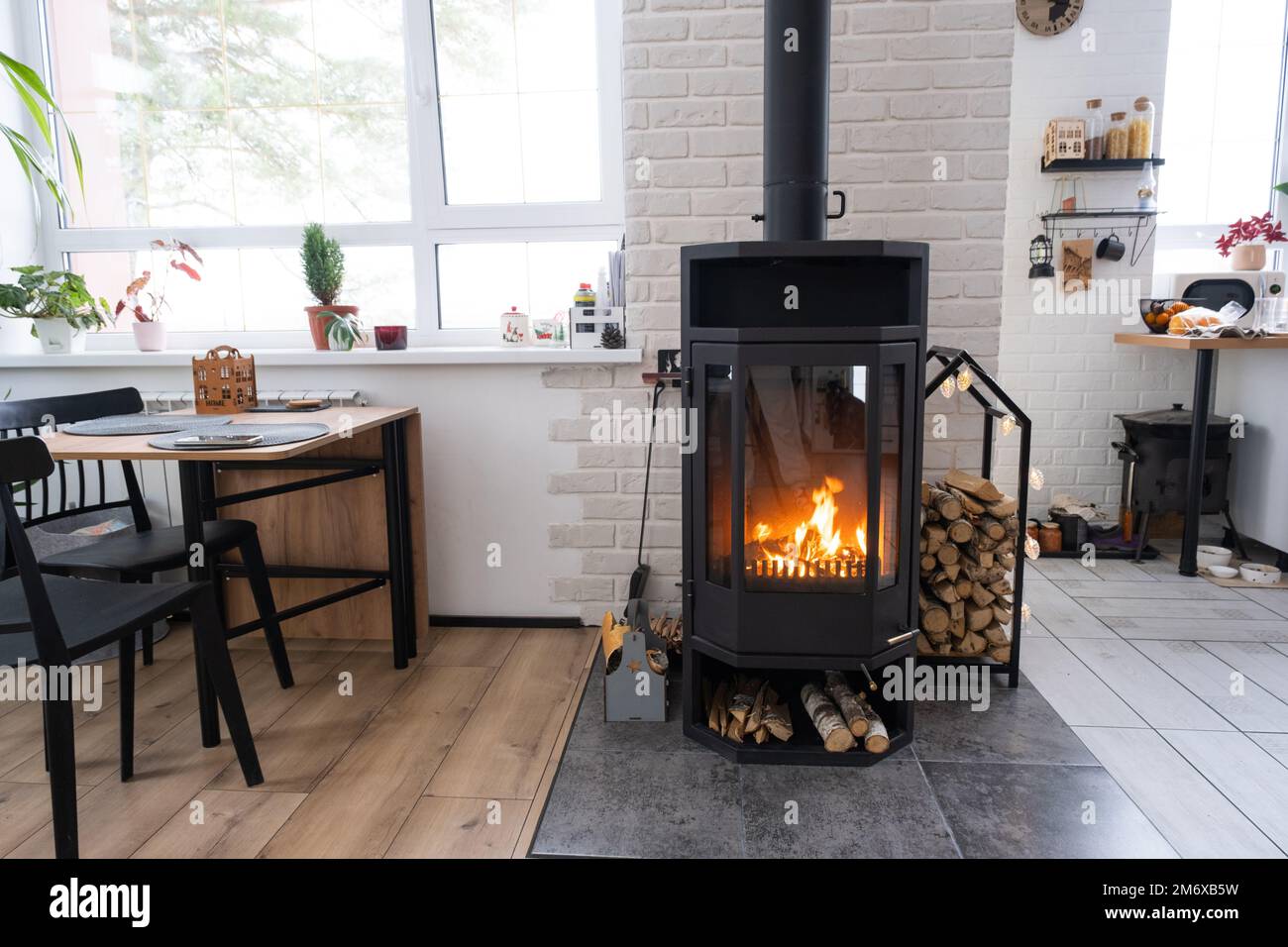Festive interior of house is decorated for Christmas and New Year in loft style with black stove, fireplace, Christmas tree. War Stock Photo