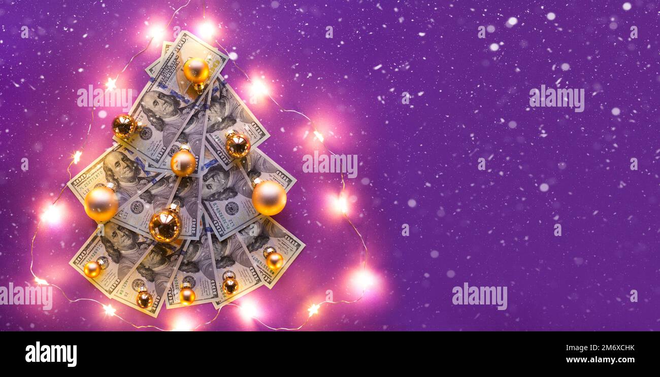 Christmas tree of 100 dollar bills on purple background with copyspace