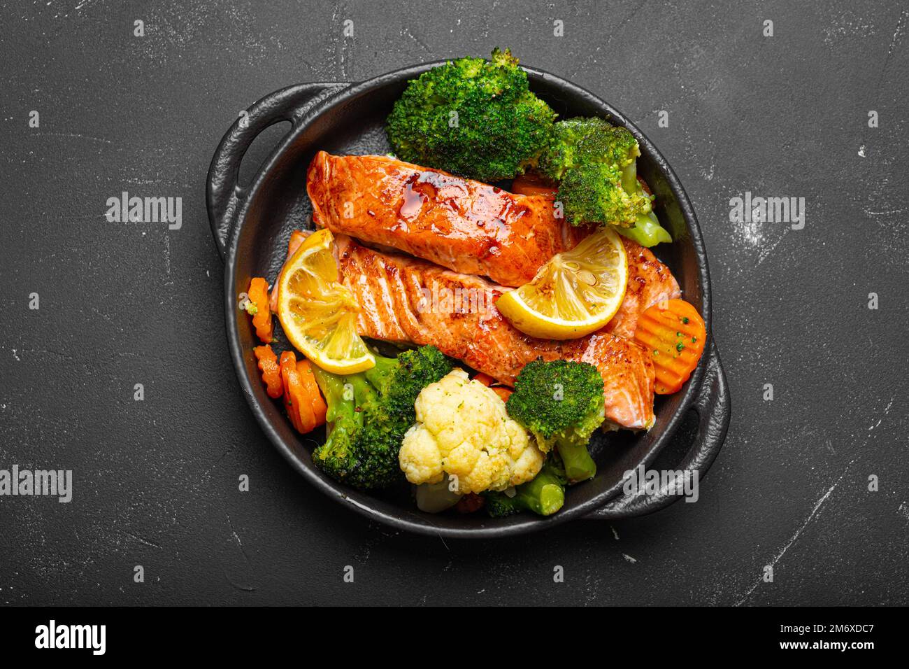 Healthy baked fish salmon steaks, broccoli, cauliflower, carrot in cast