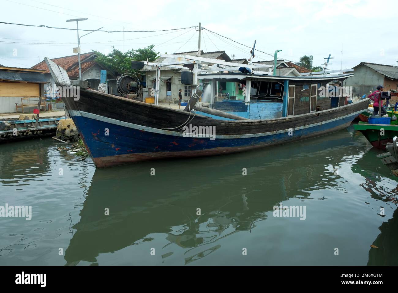 Lampung, Indonesia 9 November 2022: Rows of fishing boats on the pier with shadow reflections in the water against a clear sky background Stock Photo
