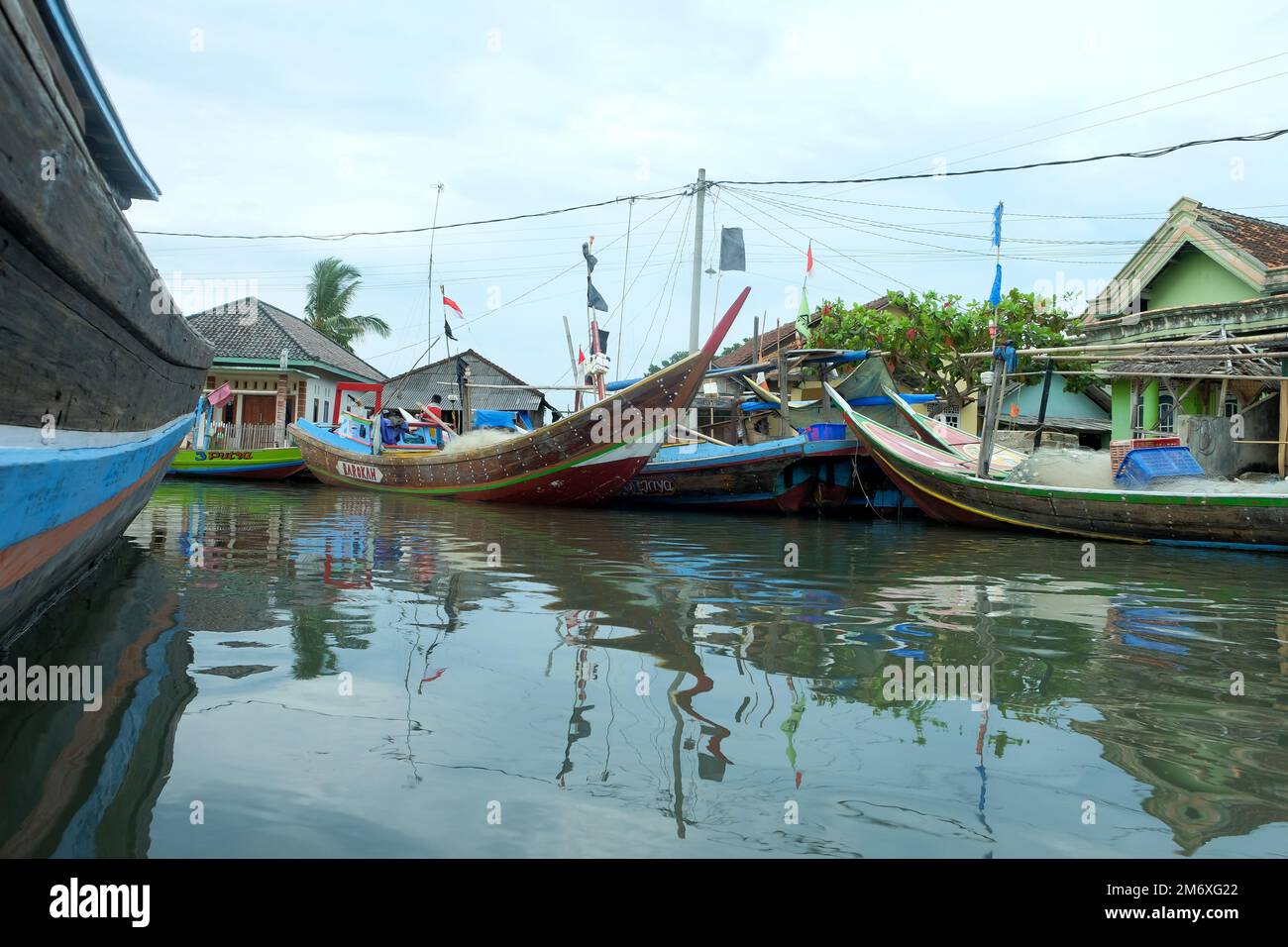 Lampung, Indonesia 9 November 2022: Rows of fishing boats on the pier with shadow reflections in the water against a clear sky background Stock Photo