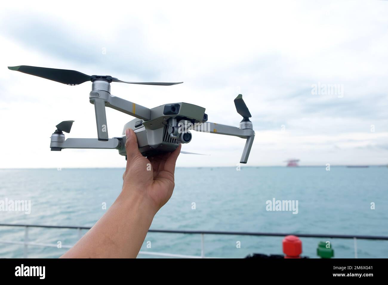 Hand reaching for drone outdoors at sunrise. Testing an aerial unmanned vehicle in nature. Sky background Stock Photo