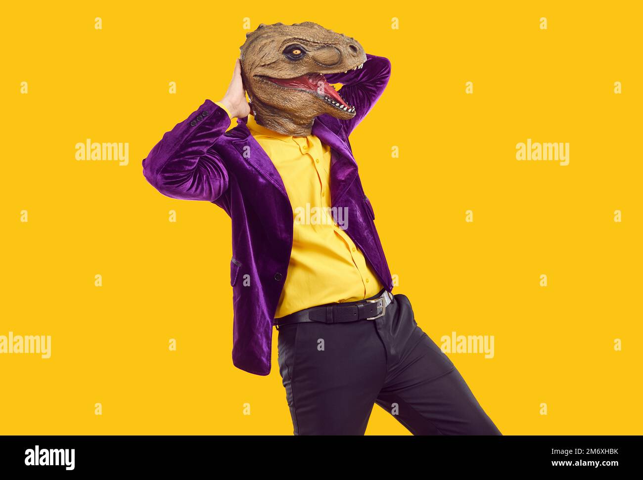 Cool party man in trendy dinosaur mask doing dance moves having fun at themed party. Stock Photo