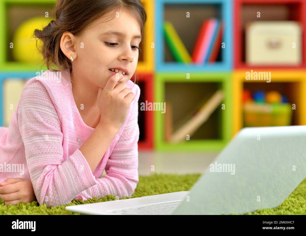 Emotional cute girl using laptop while lying on floor Stock Photo - Alamy