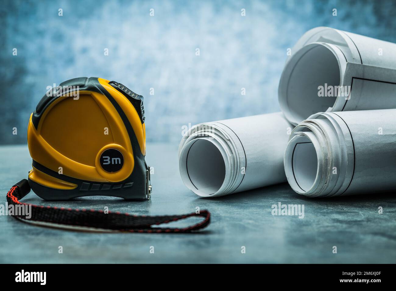 construction roulette and rolled blueprints on metalic background Stock Photo