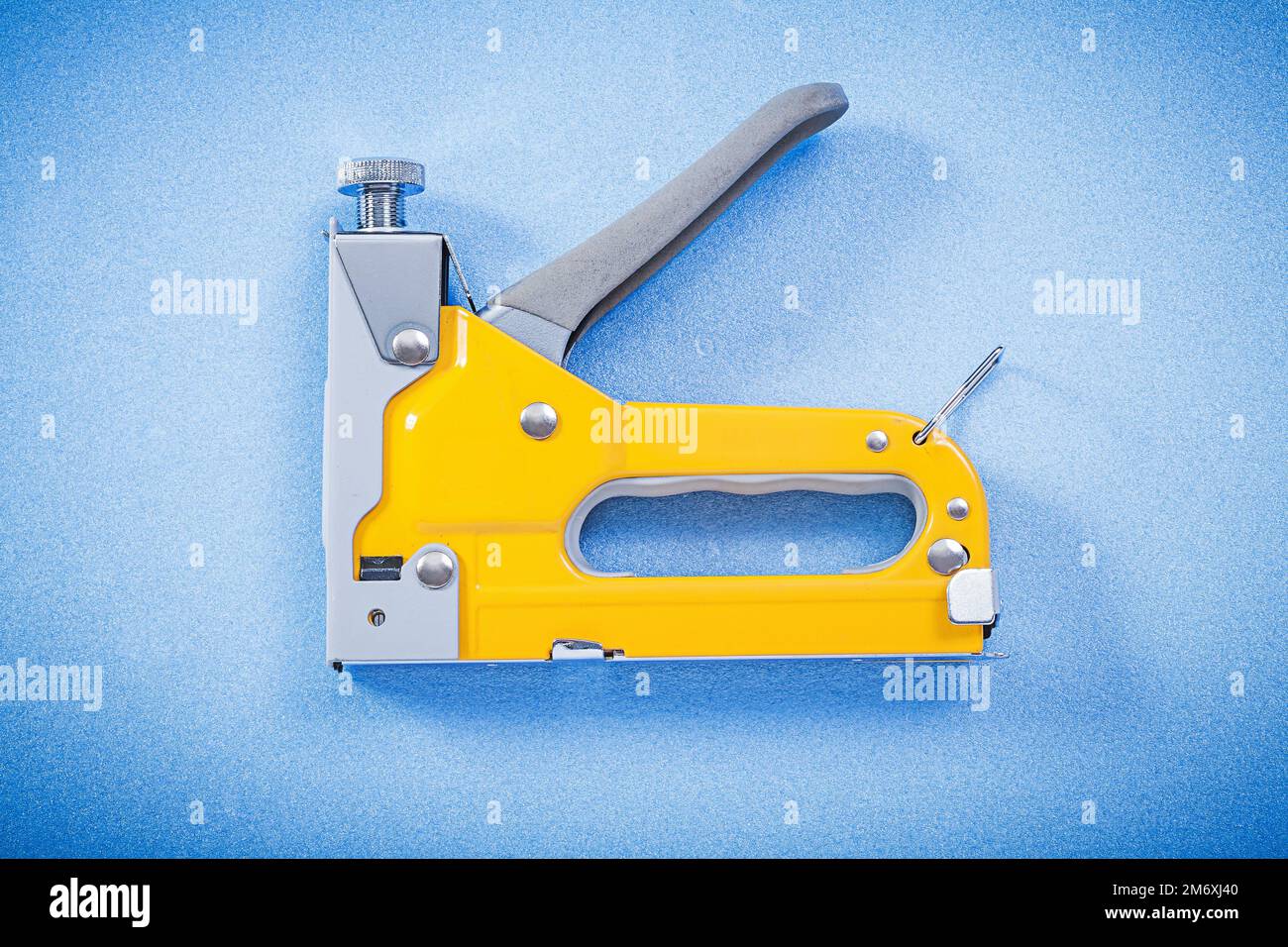 Construction stapler on blue background horizontal view. Stock Photo