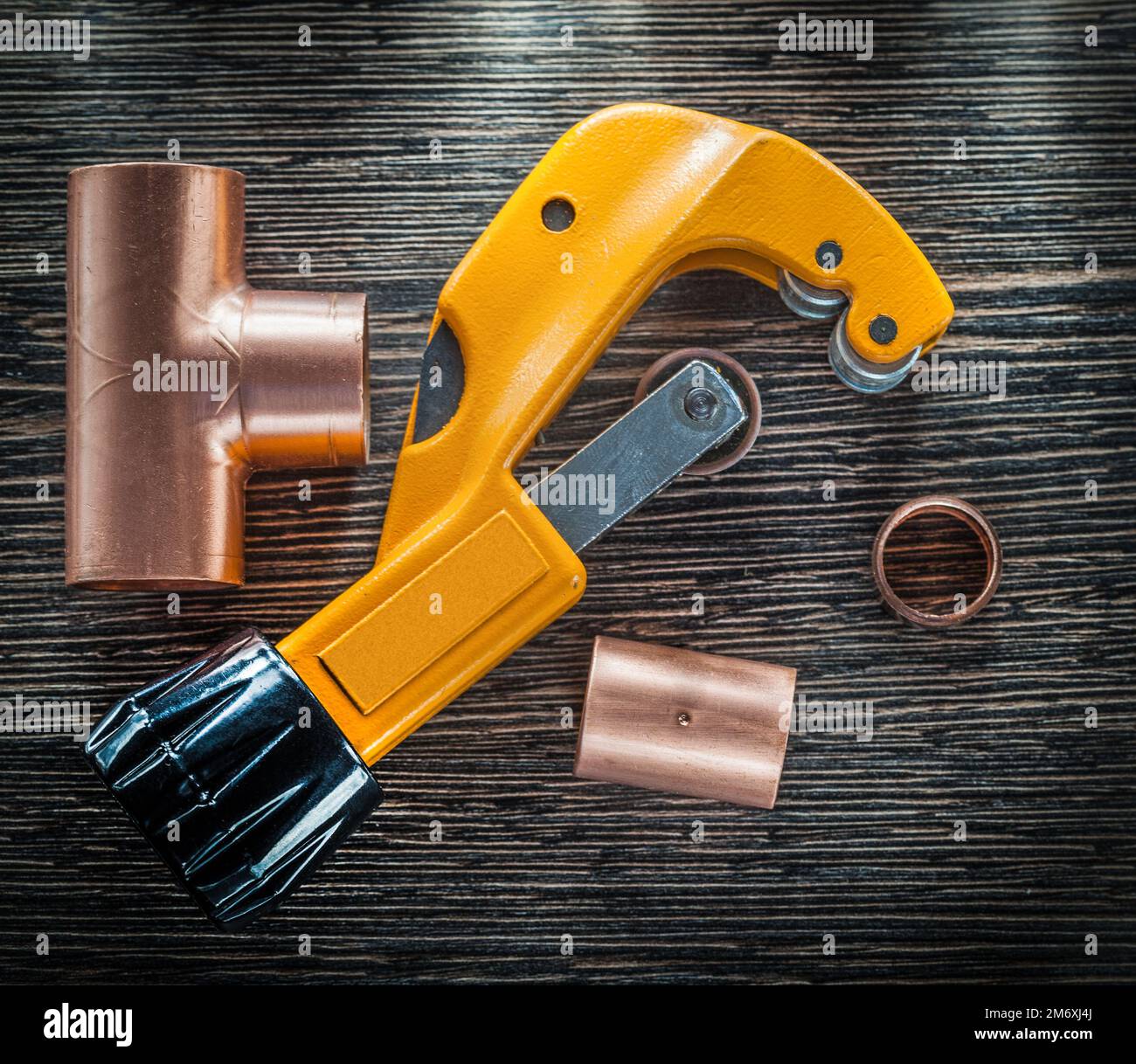 Copper water pipe cutter T-tube on wooden board. Stock Photo