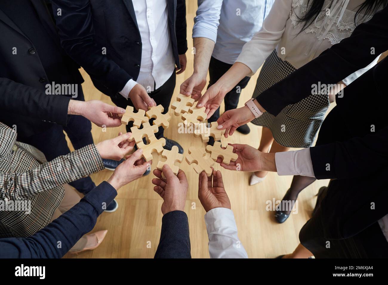 Hands man and woman in business clothes with puzzle pieces symbolize team building in office Stock Photo