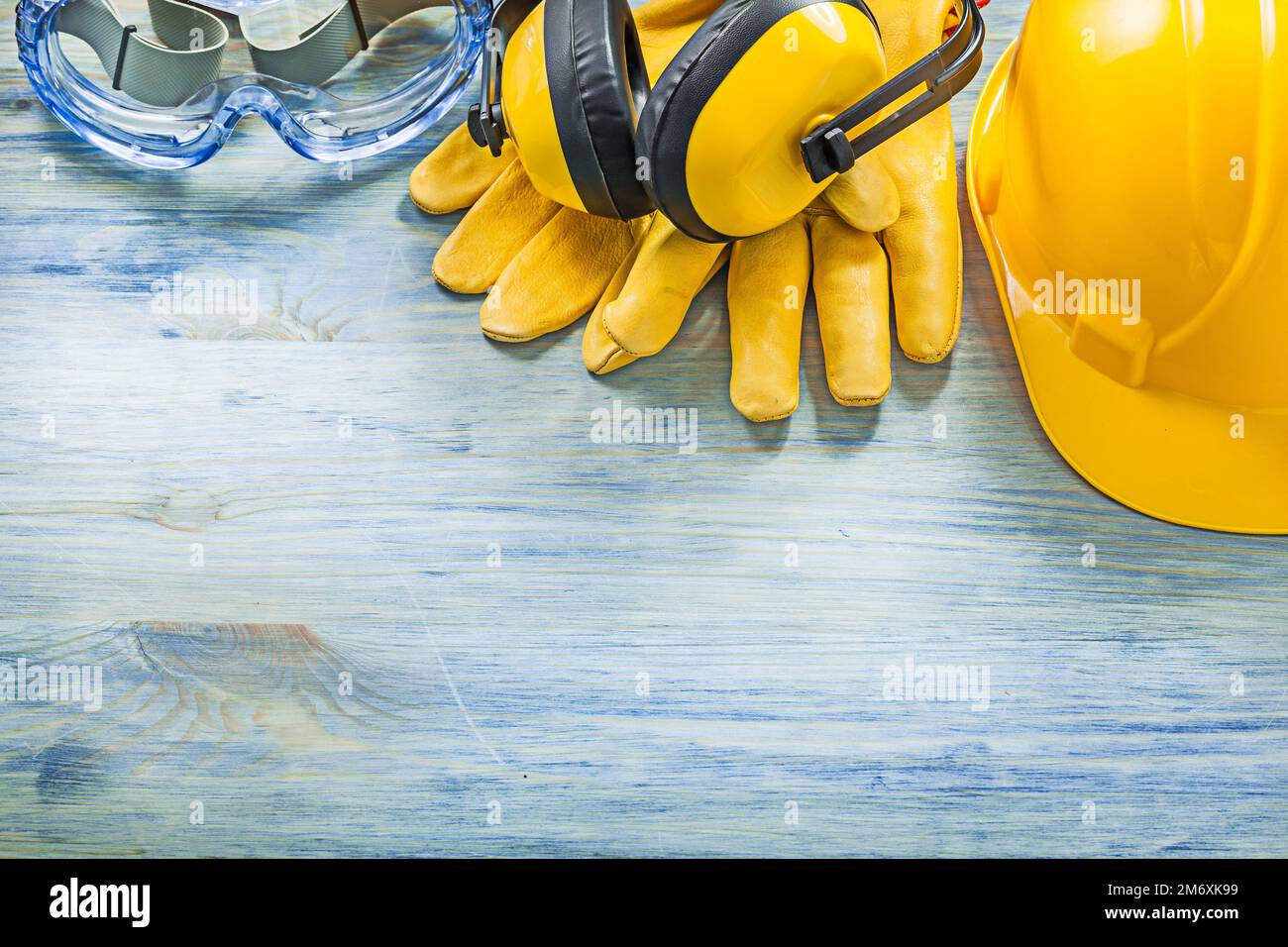 Earmuffs safety spectacles leather gloves building helmet on wood board