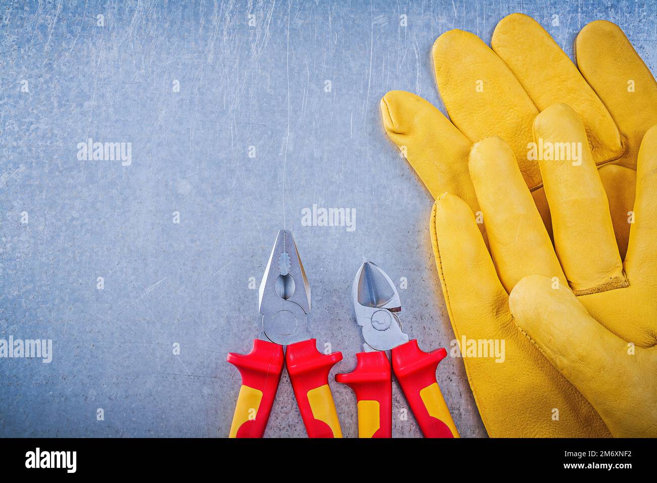Leather safety gloves pliers nippers on metallic background electricity