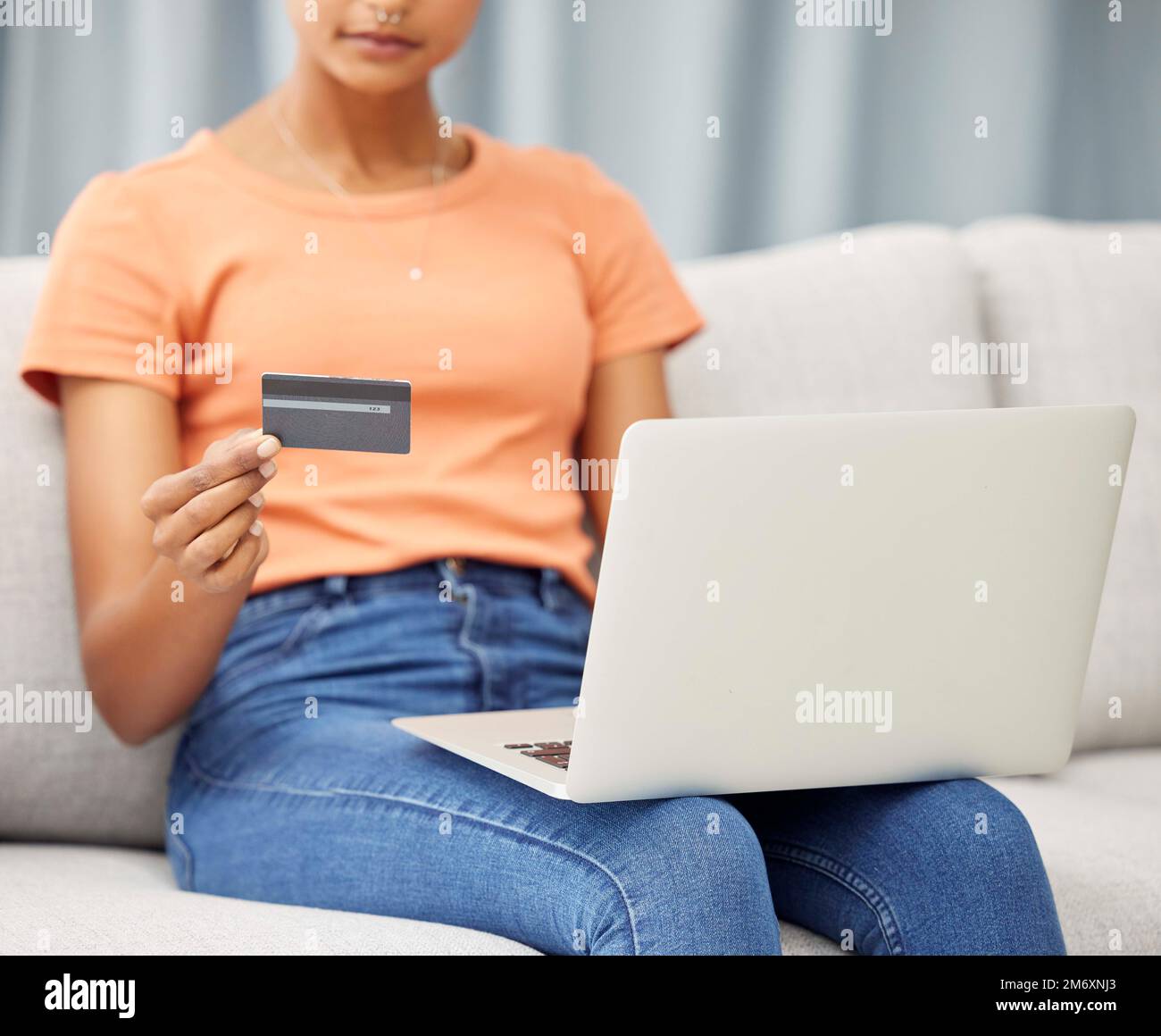 Black woman on sofa, laptop and credit card for finance, budget and