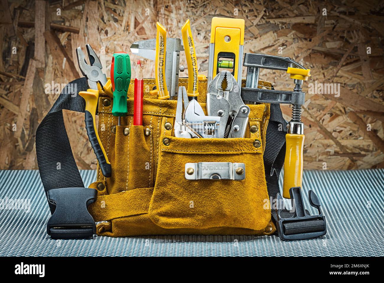 leather toolbelt with many construction tools on plywood background ...