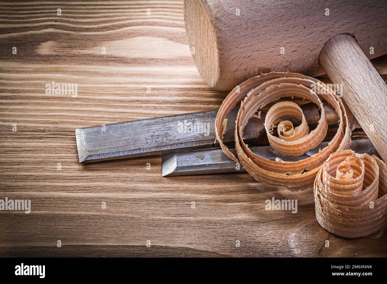 Lump hammer firmer chisels curled shavings on vintage wood board construction concept. Stock Photo