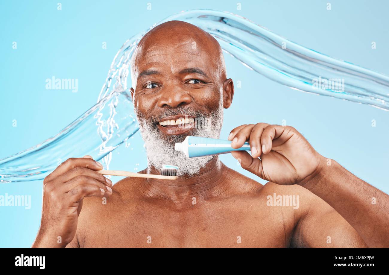 Water splash, oral hygiene and portrait of a man in a studio for mouth health and wellness. Toothpaste, toothbrush and elderly African guy brushing Stock Photo