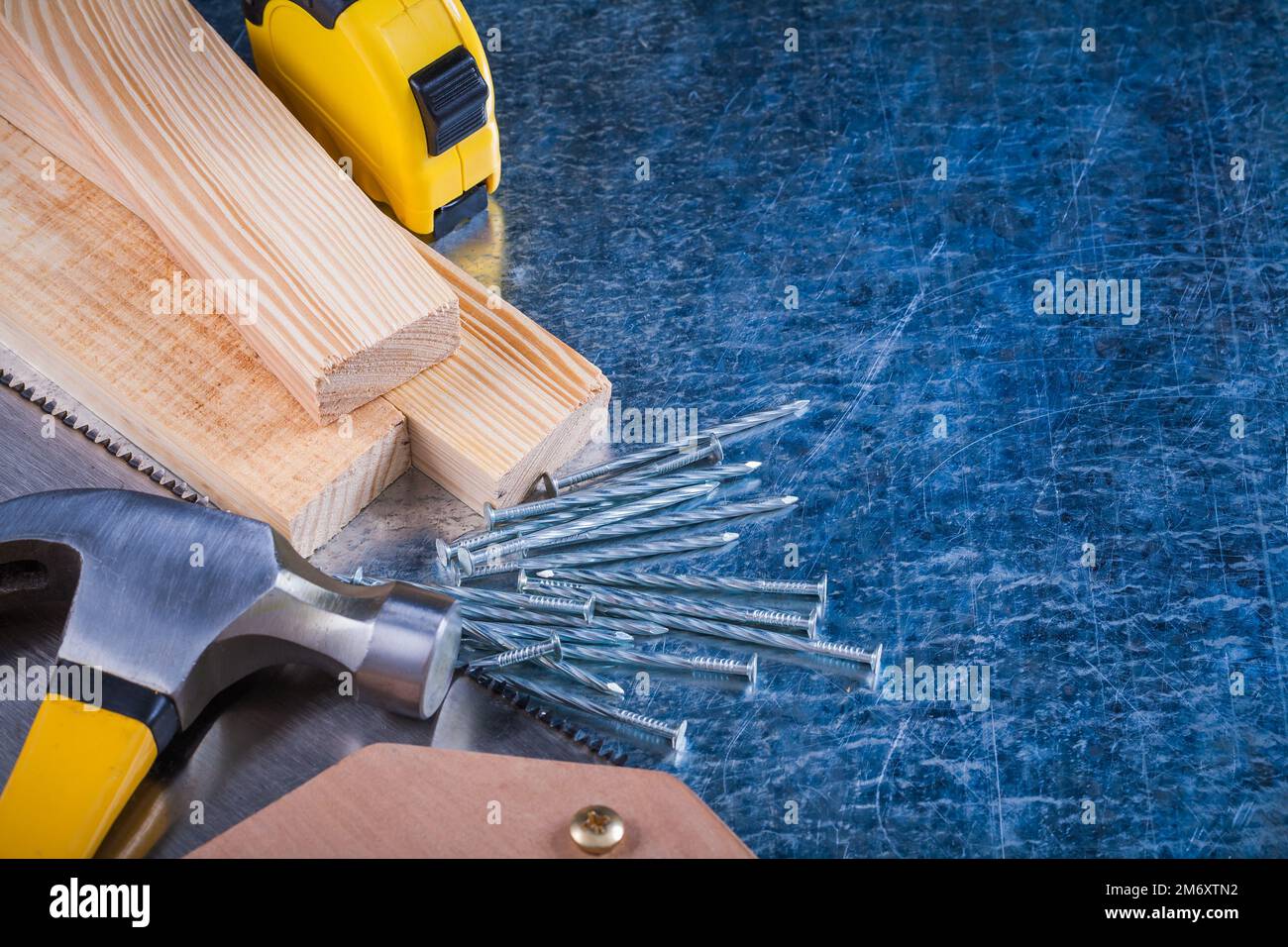 Composition of metal nails hammer wooden bricks hacksaw tapemeasure on