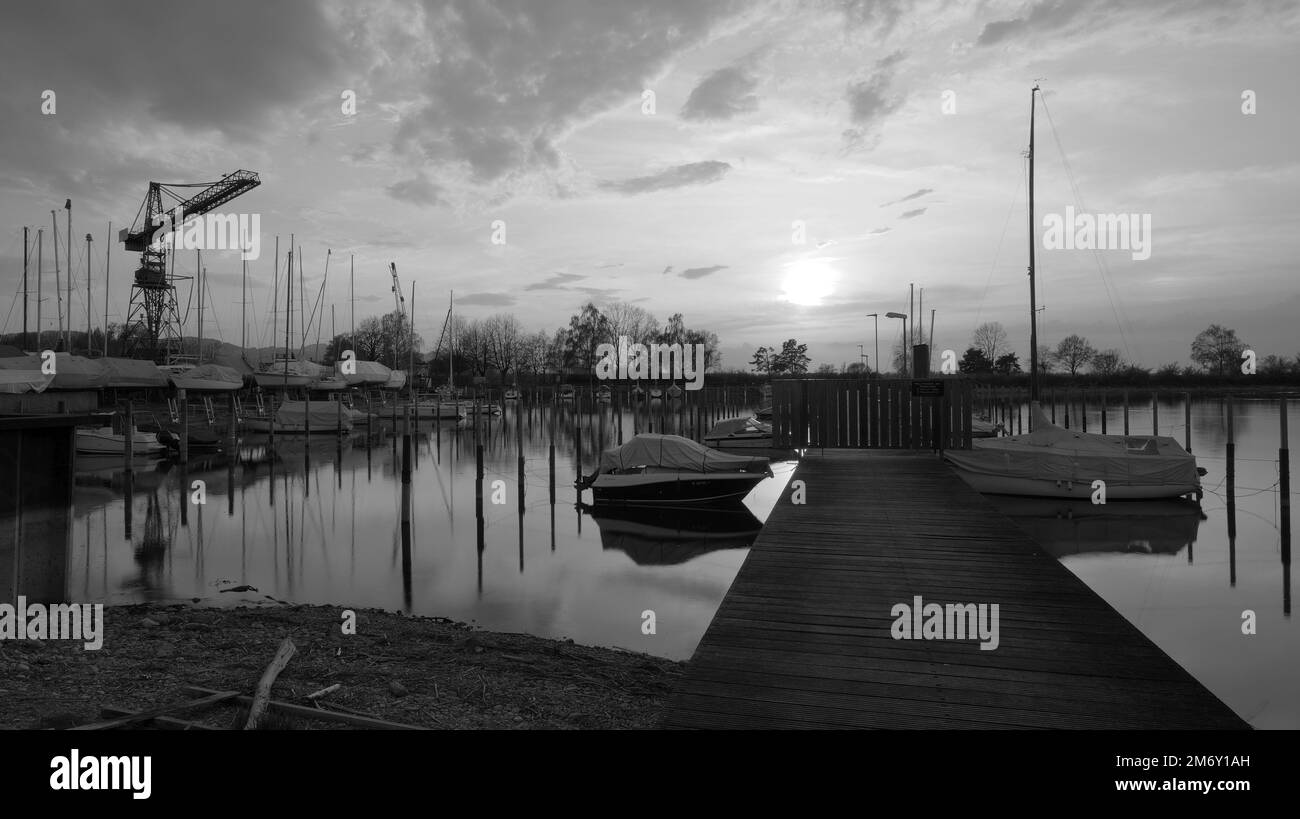 Jetty at harbor of Hard in Austria at Lake Constance in sunset with crane in picture in black and white Stock Photo
