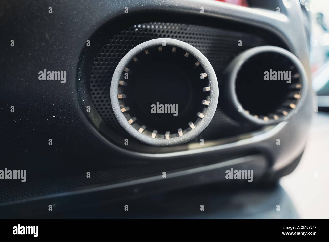detail rear view of black sport car pair of exhaust pipes with dark