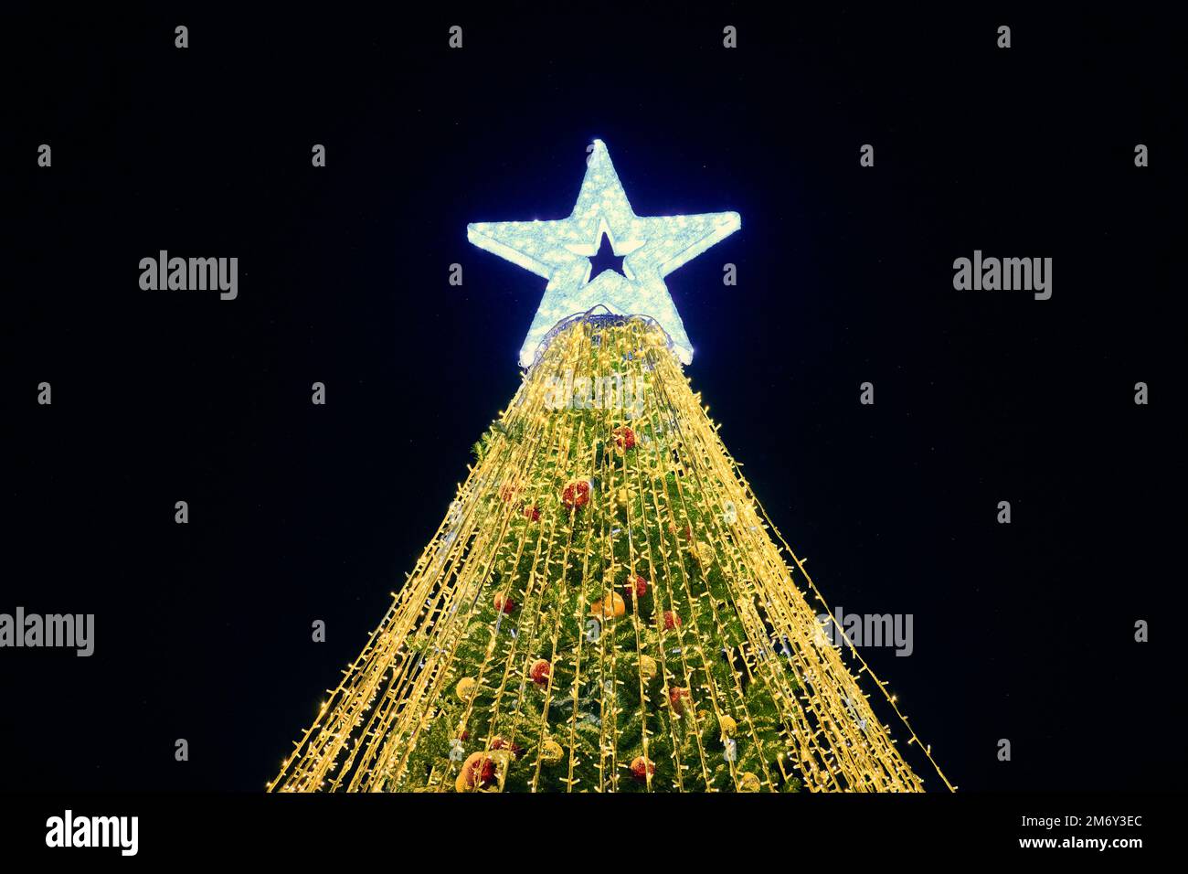 Christmas tree with big white star topper decorated yellow garlands and ...
