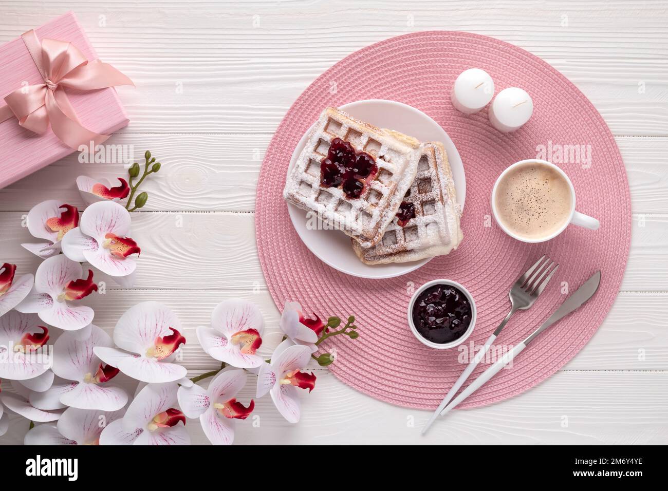 Belgian waffles with latte and orchid flower on white wooden table. Top view. Mother's day
