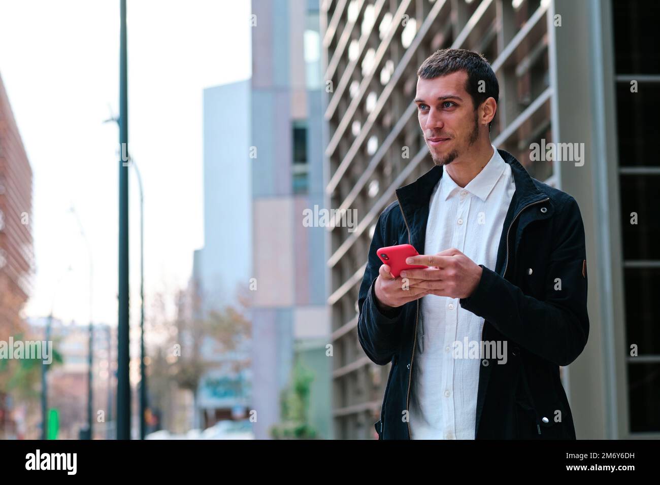 Man using a mobile phone while standing outdoors. Stock Photo