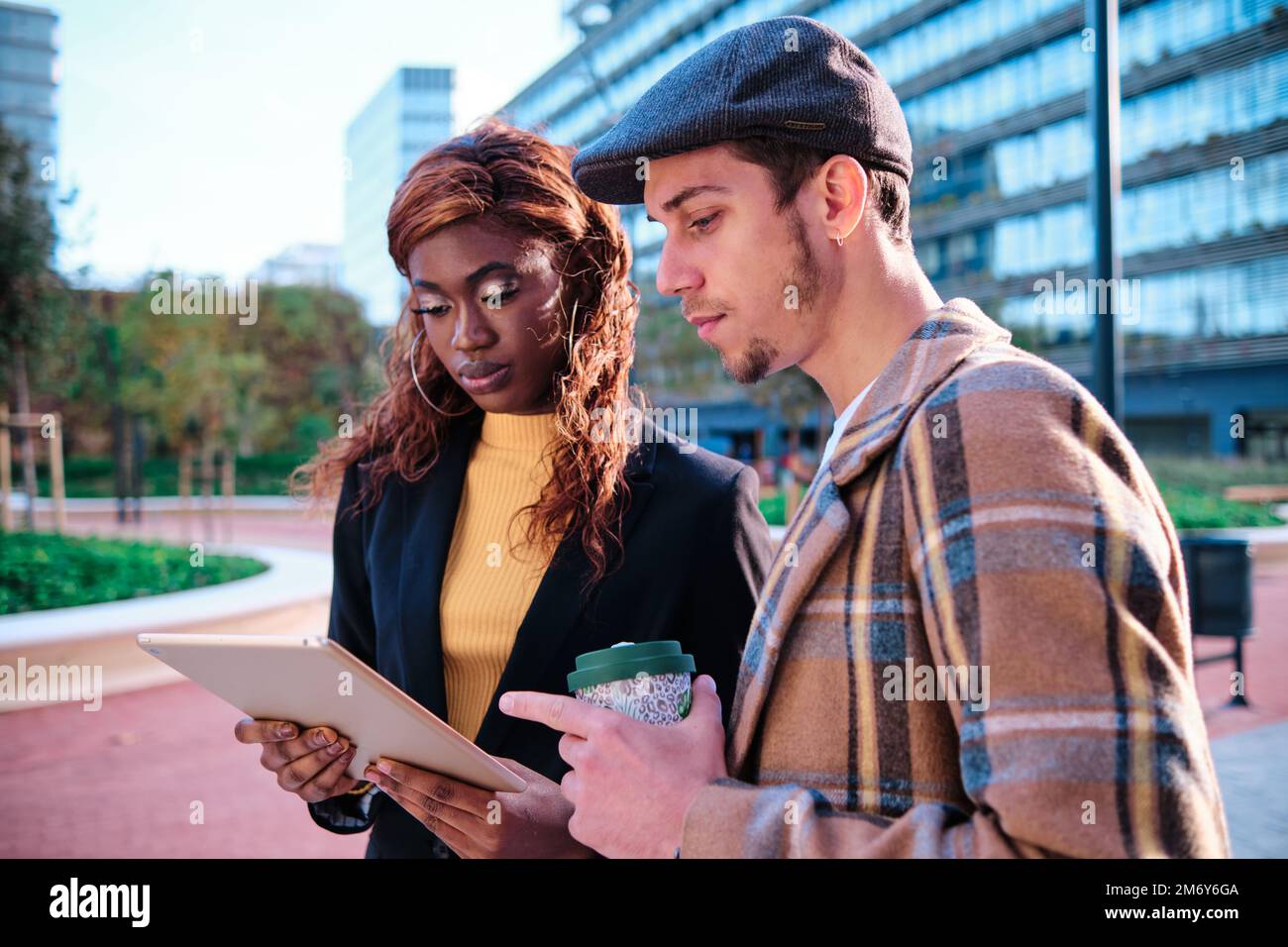 Coworkers using a digital tablet while discussing about work standing outdoors in the financial district. Stock Photo