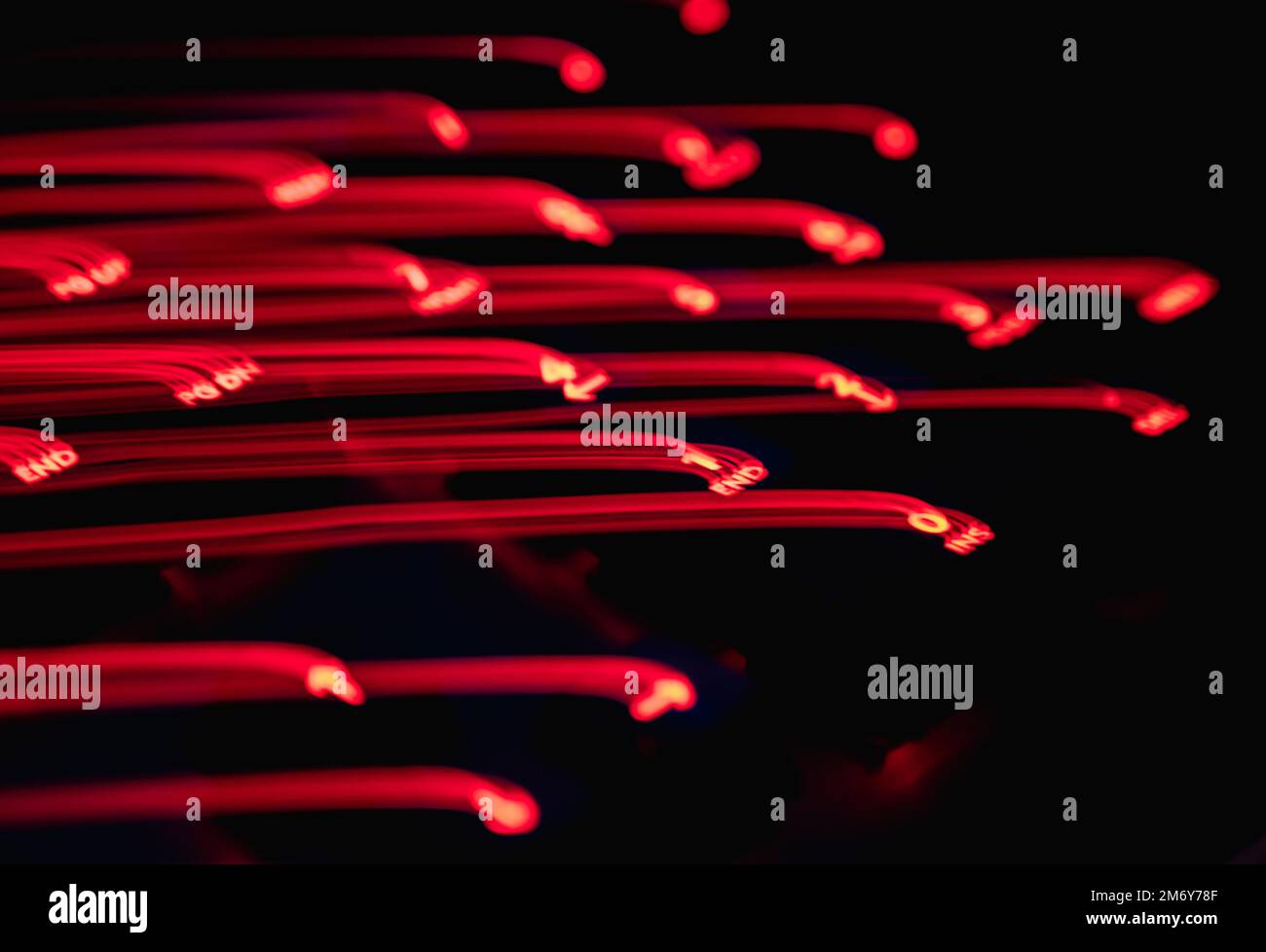 Light painting keyboard letters. Beautiful colorful background. Long exposure light painting.Red curved lines in vibrant neon on black background. Stock Photo