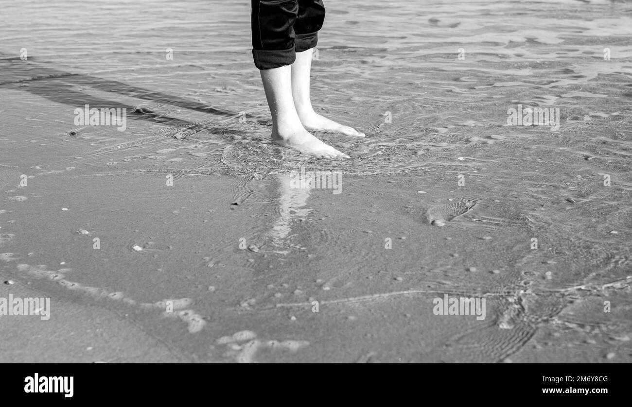 water foot photograph.Summer concept with beach and human foot.Freedom concept.Human feet in water.Human feet on the beach in summer.Holidays summer Stock Photo