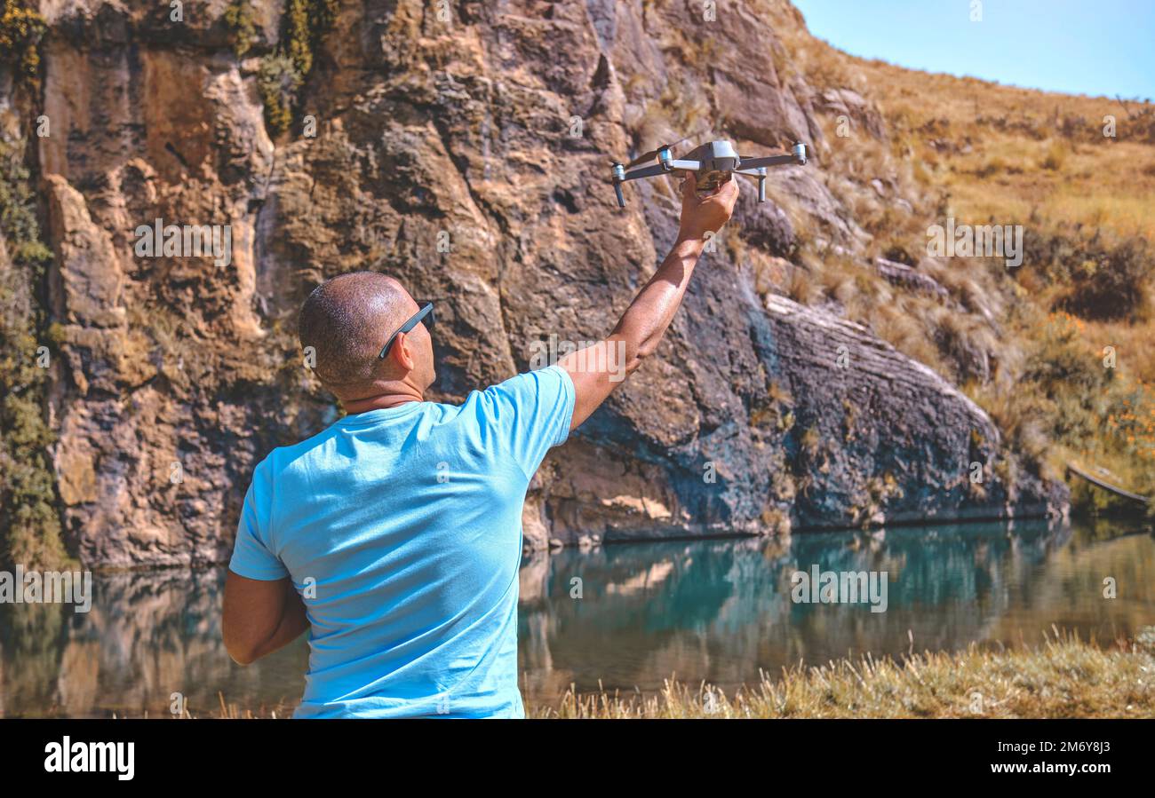 Young man with modern drone in mountains, back view Stock Photo