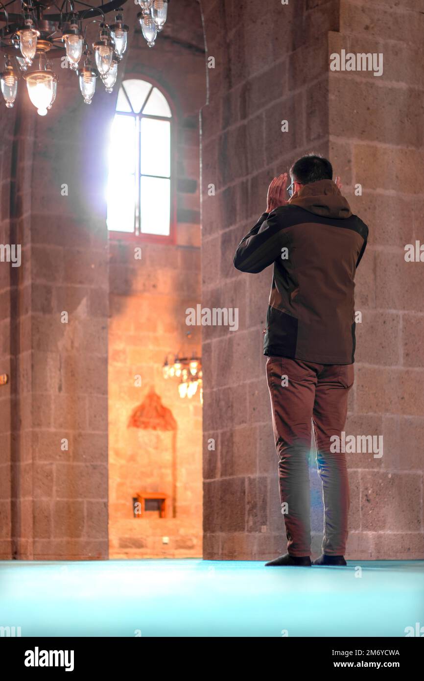 Standing photo of a man praying inside the mosque. Islamic concept. Stock Photo