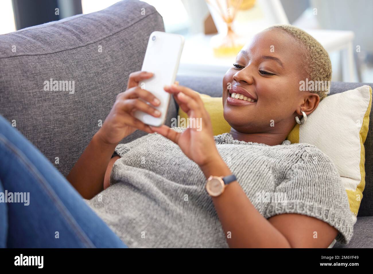 Social media, relax and black woman with a phone for communication, mobile chat and app on the sofa. Connection, internet and calm African girl with a Stock Photo