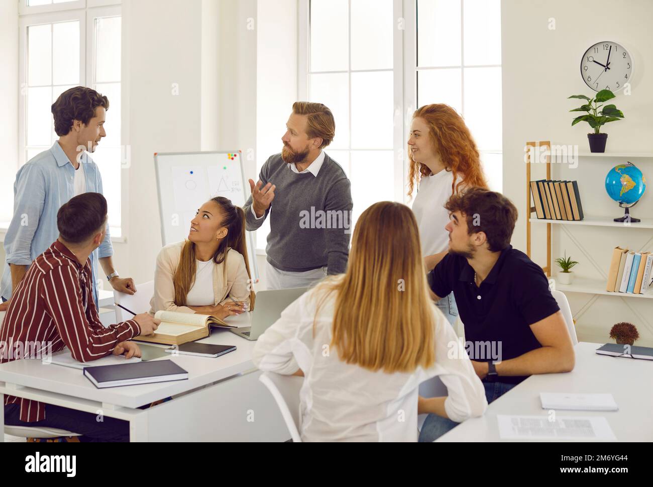 Creative friendly male teacher talks and discusses with students