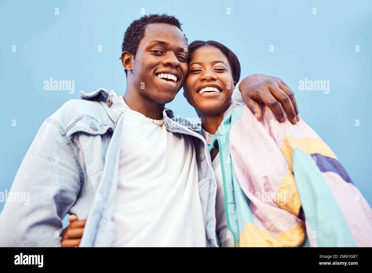 Couple, love or bonding hug by city wall background in trust, security or support in relax urban date, fun activity or holiday. Portrait, happy smile Stock Photo