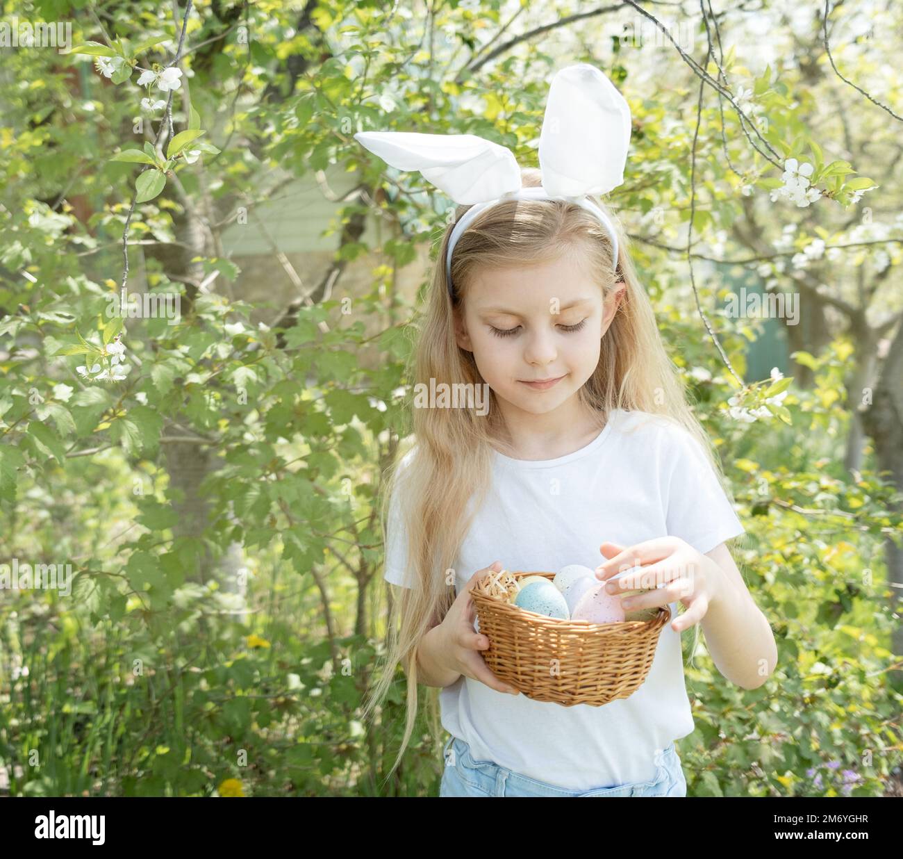 Cute little child wearing bunny ears on Easter day. Girl holding basket ...