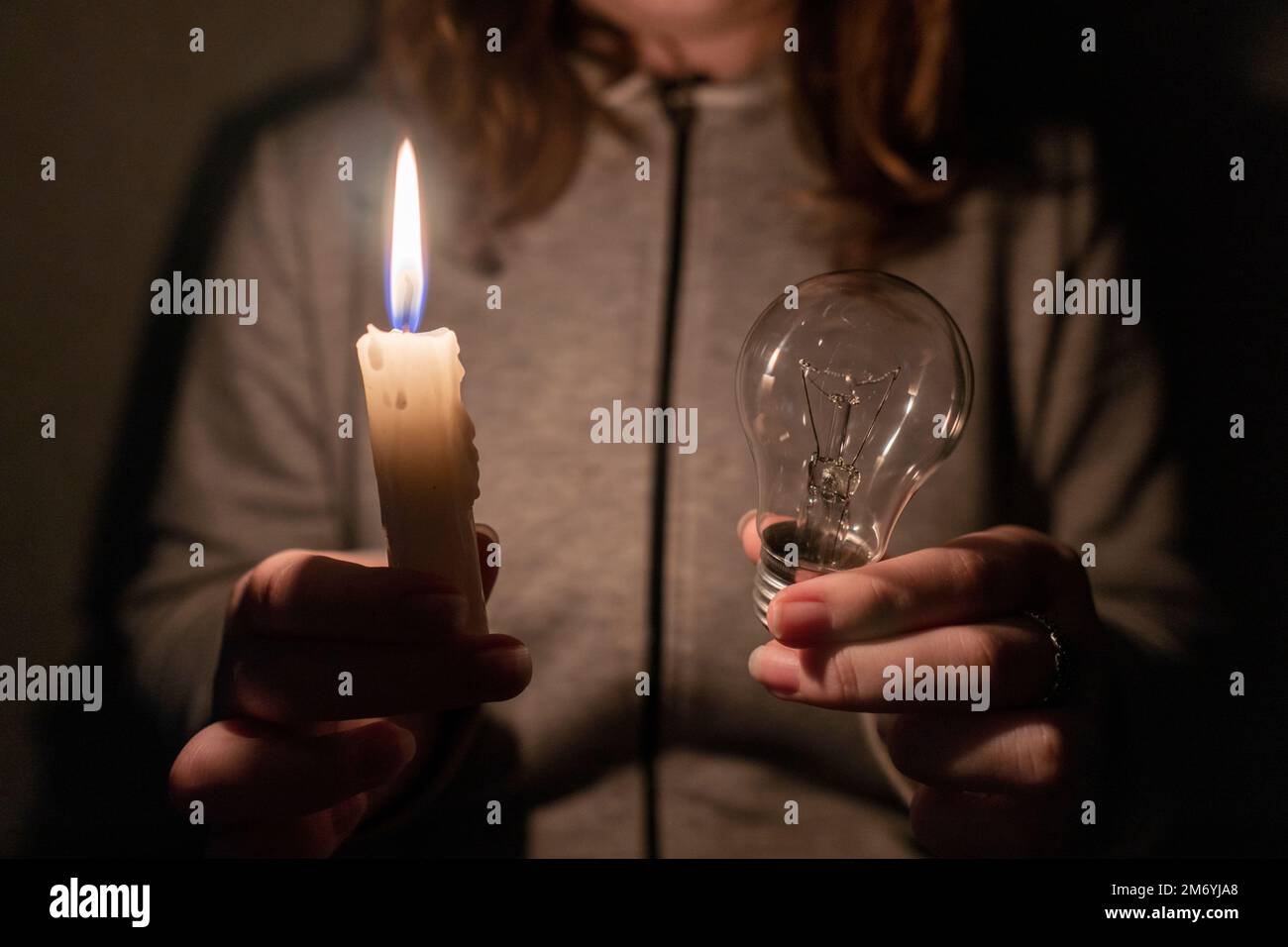 https://c8.alamy.com/comp/2M6YJA8/girl-holds-an-electric-light-bulb-and-a-burning-candle-in-her-hands-blackout-destruction-of-infrastructure-energy-crisis-power-outage-concept-2M6YJA8.jpg