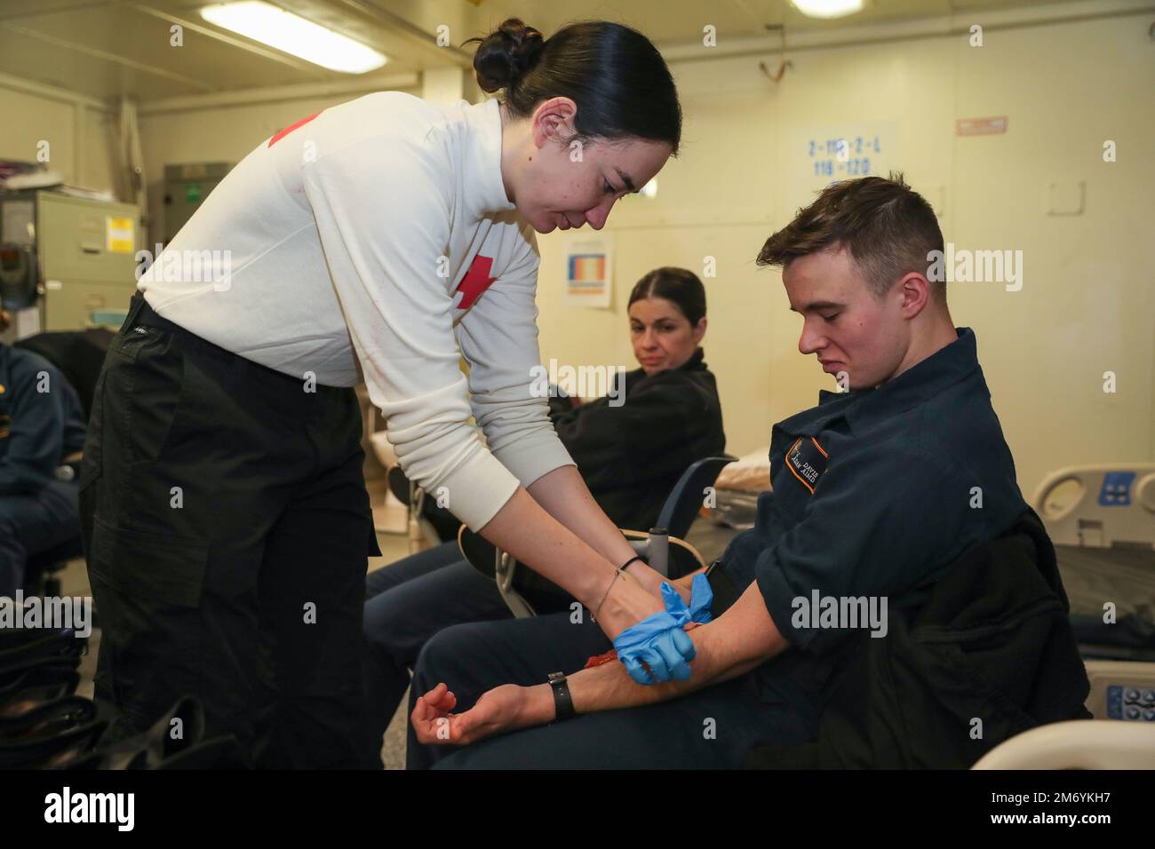 Hospitalman Sarah Chinquee, left, from Browns Mills, New Jersey, assigned to USS Gerald R. Ford’s (CVN 78) medical department, places a simulated laceration wound on Aviation Machinist's Mate Airman Joseph Davis, from Asheville, North Carolina, assigned to Ford’s aircraft intermediate maintenance department, prior to a general quarters drill, April 20, 2022. Ford is underway in the Atlantic Ocean conducting carrier qualifications and strike group integration prior to operational deployment. Stock Photo