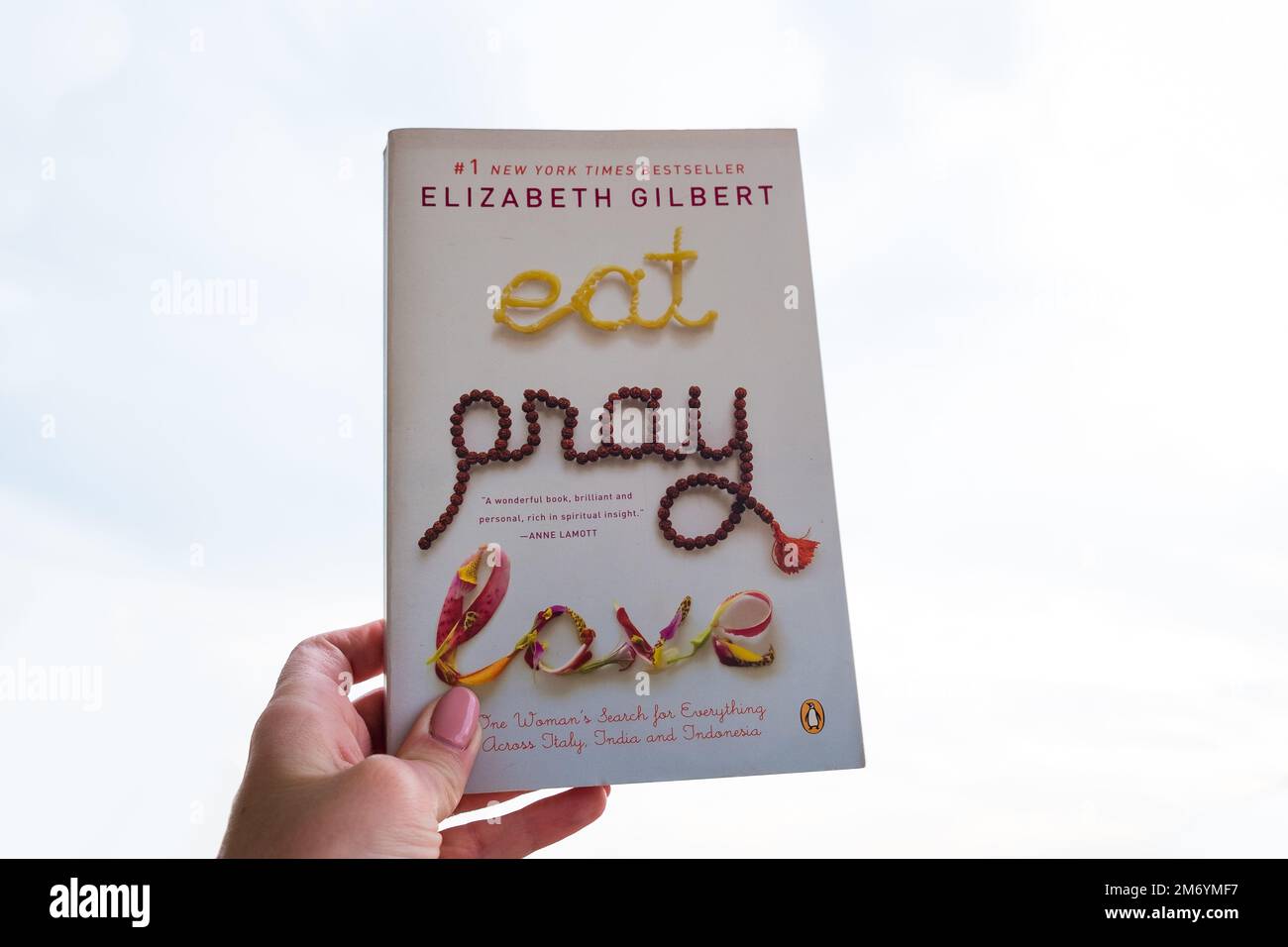 Milano, Italy - May 4, 2022: Hand holding New York Times bestseller by Elizabeth Gilbert 'Eat. Pray. Love'. Stock Photo