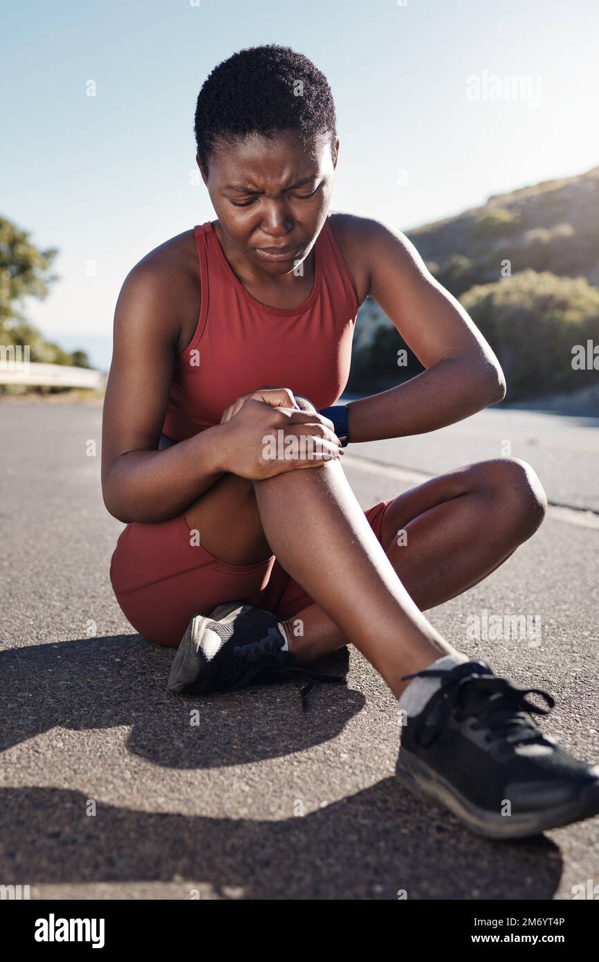Black woman, knee and sports injury on asphalt in pain from accident