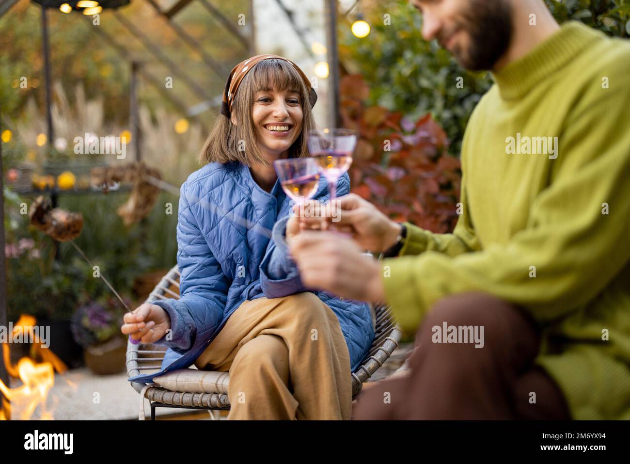 Young couple spending dinner time by the fire at backyard Stock Photo