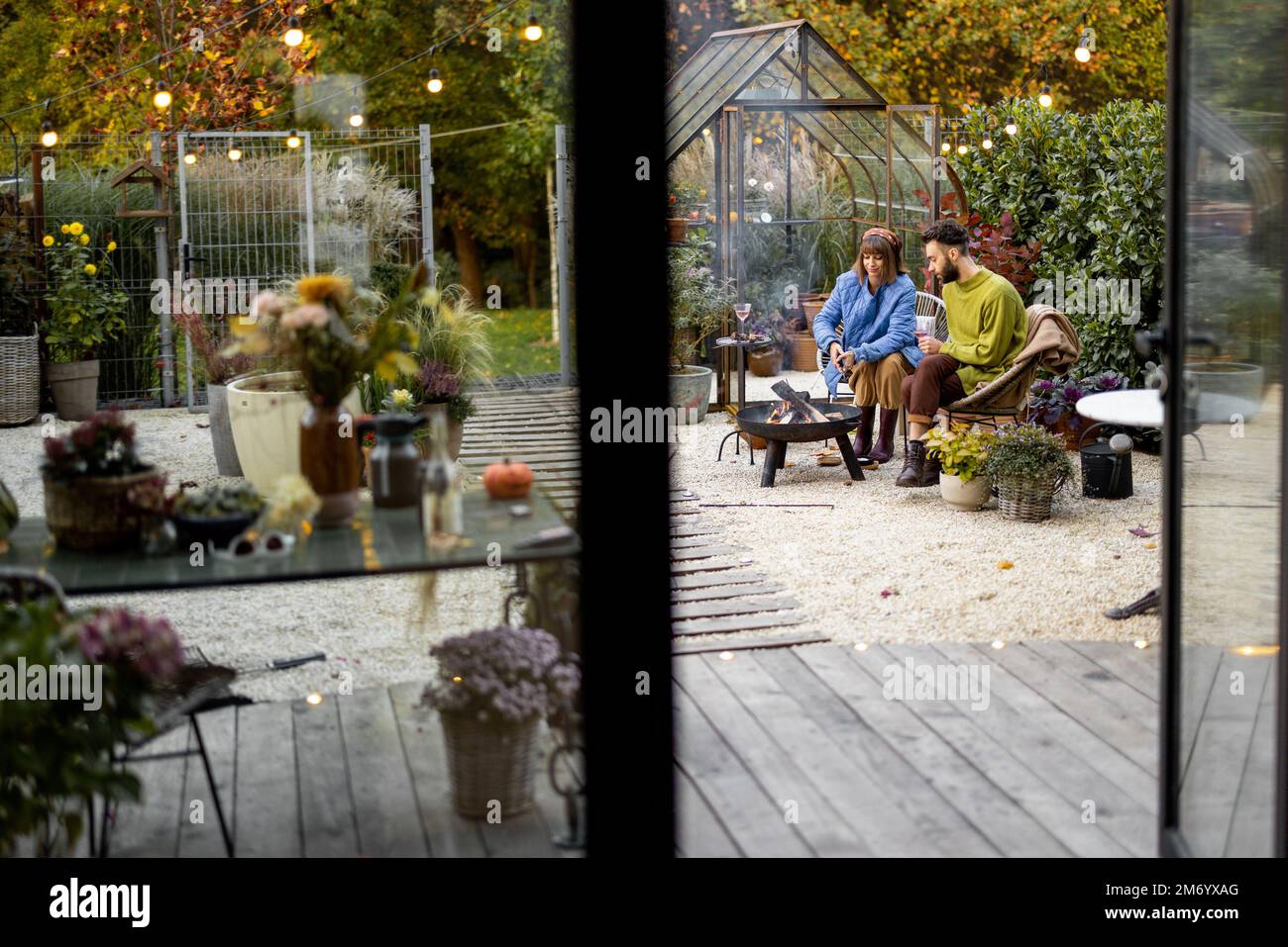 Young couple spending dinner time by the fire at backyard Stock Photo
