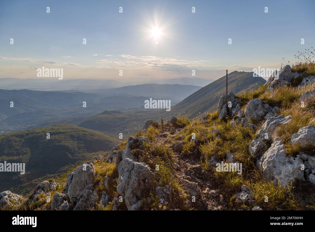 Slopes around the mountain with low grass and karst rocks at sunset Stock Photo